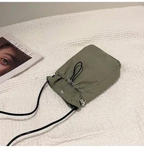 Vista detallada del mini bolso bandolera minimalista verde oliva de lona resistente