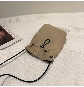 Vista detallada de un mini bolso de lona caqui con cordón y estilo muy minimalista