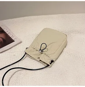 Detalle del bolso de lona para teléfono en color crema con cierre de cordón y correa