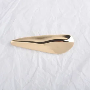 Détail d'une broche métallique irrégulière dorée brillante pour accessoires de manteau.
