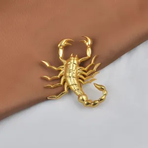 Vue détaillée d'une broche scorpion dorée affichant des textures métalliques complexes.