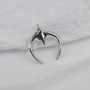 Detailed macro view of a silver star and moon shaped stainless steel brooch on white paper