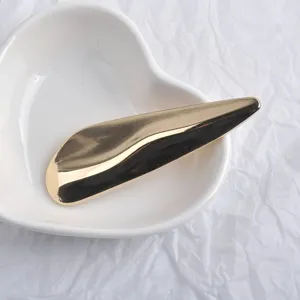 Gros plan d'une broche en métal doré en forme de vague dans un plat en forme de cœur