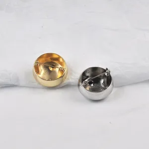 Detailed back view of minimalist round metal brooches in polished gold and silver finishes