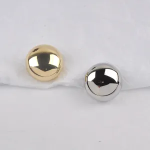 Detail of round metal brooches with high-gloss gold and silver finishes on white paper.
