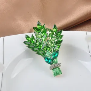 Nahaufnahme einer grünen Kristall-Blumenstrauß-Brosche mit goldfarbenen Details