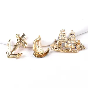 Detail view showing the back pin mechanism of gold nautical anchor and sailboat brooches.