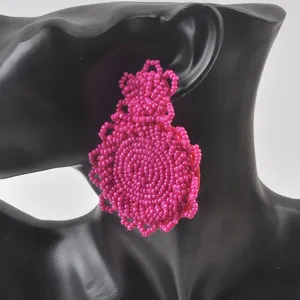 Vista dettagliata di orecchini pendenti rosa fatti a mano in perline su un manichino nero
