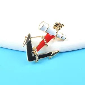 Detailed view of nautical enamel anchor and telescope brooch with elegant gold metal finish