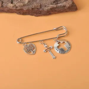 Vintage silberne Sicherheitsnadel-Brosche mit Herz-, Lebensbaum- und Kreuzanhängern auf Orange