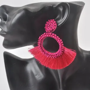 Dettaglio macro di orecchini di perline intrecciate rosa con nappa vivace.