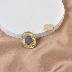 Primer plano de un broche magnético dorado que muestra el imán y el lado decorado.