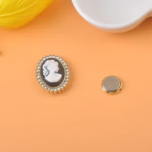 Vista detallada de un broche magnético de camafeo vintage con borde de strass y oro