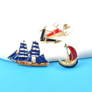 Detailed view of vintage enamel nautical brooches featuring sailboat and anchor designs.