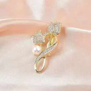 Detail einer eleganten goldfarbenen Blumenbrosche mit funkelnden Strasssteinen und Perle.