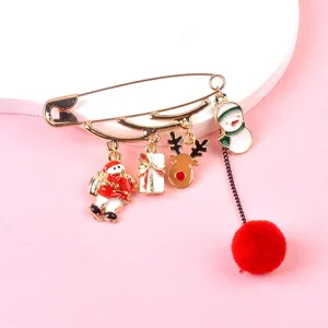 Macro detail of Christmas safety pin brooch featuring Santa and reindeer enamel charms