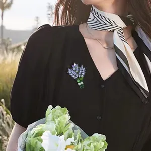 Elegante Lavendel-Strauß Brosche mit lila Kristallen auf einem schwarzen Damenkleid.
