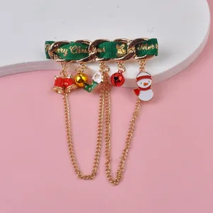 Detailed view of festive Christmas brooch with snowman and bell charms on green ribbon