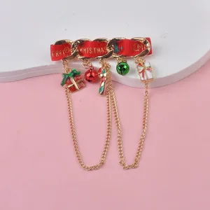 Close-up detail of festive Christmas brooch featuring red ribbon and golden charms.
