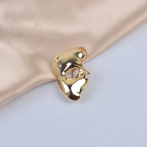 Detailed view of a vintage golden mask-shaped brooch on champagne satin fabric.