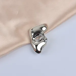 Close-up of a vintage silver metallic phantom mask brooch on elegant champagne satin fabric