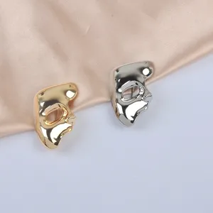 Detailed macro shot of vintage-style mask brooches in gold and silver plating.