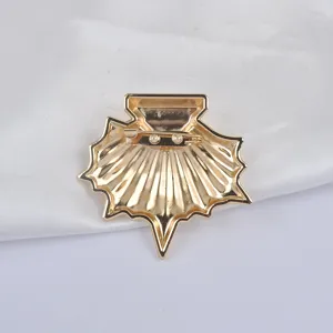 Vue détaillée du dos d'une broche coquille dorée avec son épingle de fixation métal.