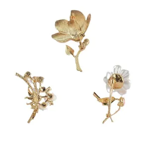 Achteraanzicht van bloemenbroches met goudkleurige metalen afwerking en speldsluiting.