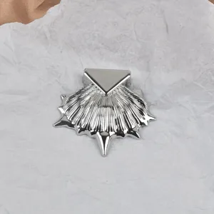 Détail d'une broche en forme de coquillage argenté avec un accent triangulaire chic