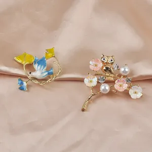 Detailaufnahme von eleganten Emaille-Friedenstaube- und Perlen-Eulen-Broschen