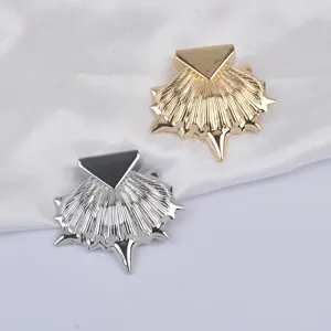 Vue macro détaillée de broches de mode métalliques en forme de coquille en or et argent.