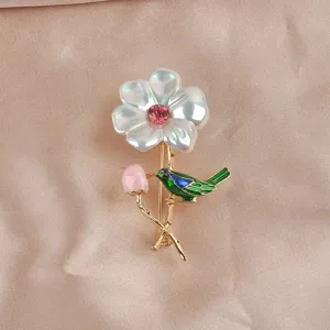 Detailopname van een elegante parelmoer kristallen bloem en vogel speld op zijde.