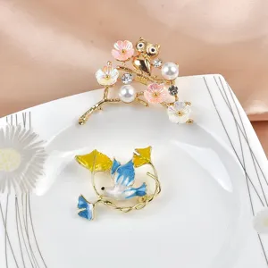 Detailansicht eleganter Emaille-Broschen mit Friedenstaube, Eule und Perlenbesatz