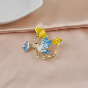 Elegantes Detail einer Emaille-Friedenstauben-Brosche mit Ginkgoblättern auf Satin
