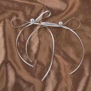 Detail von eleganten weißen langen Schleifenohrringen mit Perlen auf brauner Seide