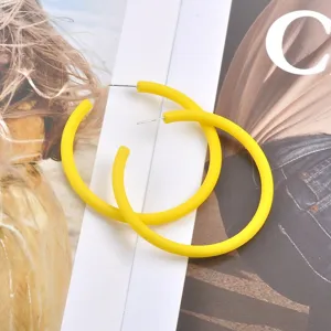Nahaufnahme von leuchtend mattgelben C-förmigen Creolen auf Modemagazin präsentiert