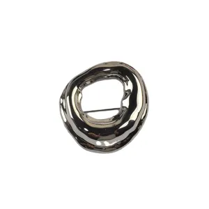 Close-up of minimalist irregular geometric circular brooch with glossy metallic finish