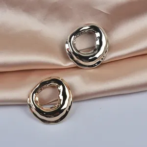 Macro detail showing gold and silver irregular geometric brooches on silk fabric.
