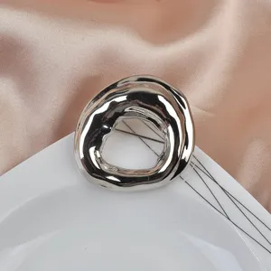 Macro detail showing irregular geometric silver brooch on silk and ceramic background