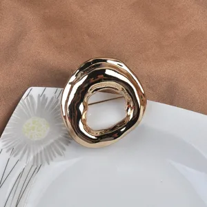 Detailed close-up of a gold minimalist irregular geometric round brooch on a plate