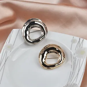 Detailed macro view of irregular geometric round brooches in gold and silver finishes.