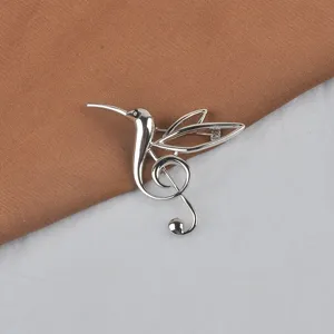 Makroansicht einer silbernen Kolibri-Brosche mit elegantem Violinschlüssel-Design