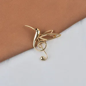 Detail einer eleganten vergoldeten Kolibri-Brosche mit integriertem Musiknoten-Design