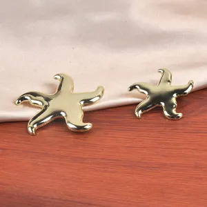 Vue macro détaillée de broches d'étoiles de mer en or poli sur fond satiné élégant.