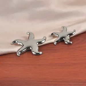 Gros plan de deux broches étoile de mer en argent poli sur satin et bois.