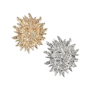 Détail des broches soleil en métal de style rétro avec finitions dorées et argentées.