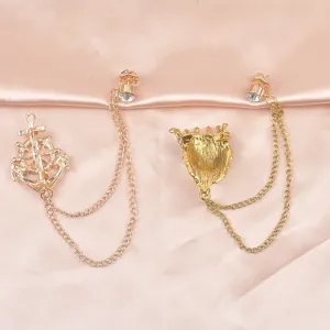 Detailansicht der Rückseite von goldenen Löwen- und Anker-Broschen auf rosa Satin.
