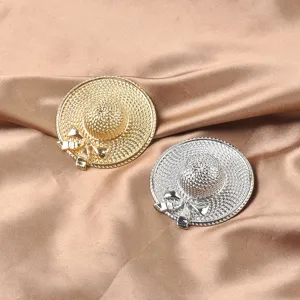 Detail of gold and silver sun hat brooches with intricate woven texture and bows