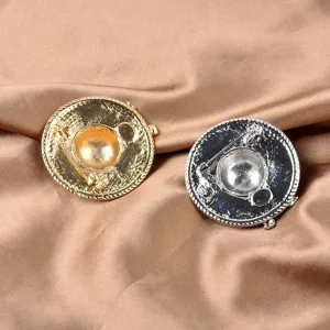 Detailed back view of gold and silver hat-shaped fashion brooch pins on satin fabric
