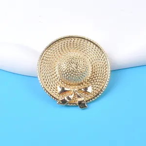 Detailed view of a golden straw hat brooch with intricate woven metal texture and bow